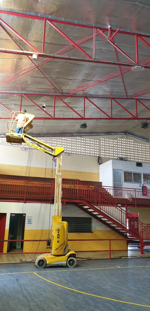 Ouvrier d'amazone prestations Guyane installant une clôture pare-ballon en intérieur en Guyane française sur la commune de Rémire-Montjoly