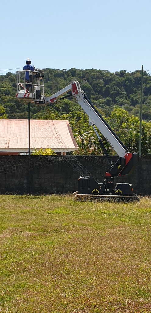 Ouvrier d'amazone prestations Guyane installant une clôture pare-ballon en extérieur en Guyane française sur la commune de Rémire-Montjoly